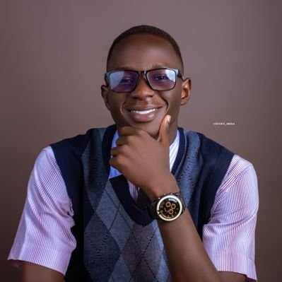 Michael Adeyemo, smiling, in glasses and a sweater vest